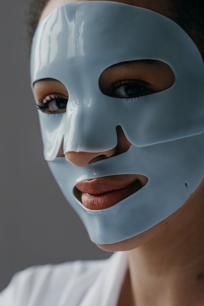 A woman with a hydrating facial sheet mask applying skincare, emphasizing beauty routine and skincare.